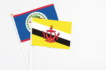 Brunei and Belize stick flags on white background. High quality fabric, miniature national flag. Peaceful global concept.White floor for copy space.