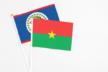 Burkina Faso and Belize stick flags on white background. High quality fabric, miniature national flag. Peaceful global concept.White floor for copy space.