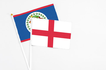 Fototapeta premium England and Belize stick flags on white background. High quality fabric, miniature national flag. Peaceful global concept.White floor for copy space.