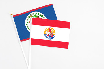 French Polynesia and Belize stick flags on white background. High quality fabric, miniature national flag. Peaceful global concept.White floor for copy space.