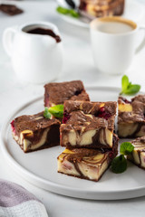 Cheesecake brownies with raspberry stacked on a white plate.