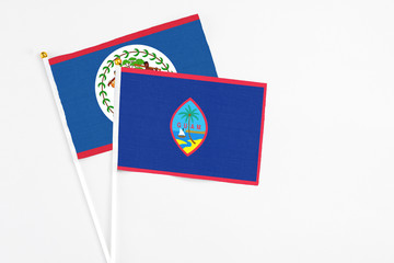 Guam and Belize stick flags on white background. High quality fabric, miniature national flag. Peaceful global concept.White floor for copy space.