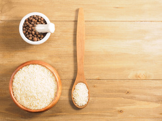 Rice and allspice on brown wooden background. Indian cuisine, ayurveda, naturopathy, modern apothecary concept