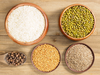 Rice, allspice, fenugreek, cumin, mung bean on brown wooden background. Indian cuisine, ayurveda, naturopathy, modern apothecary concept