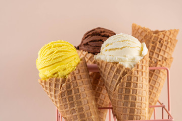 Assorted ice cream in sugar cones on pink background.