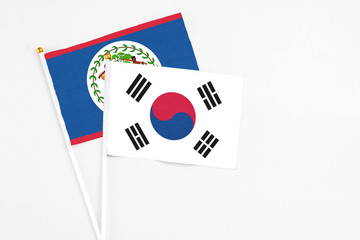 South Korea and Belize stick flags on white background. High quality fabric, miniature national flag. Peaceful global concept.White floor for copy space.