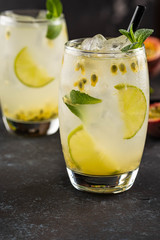 Green Lemonade drink or Mojito coctail with lime, mint, passion fruit and ice on black table.