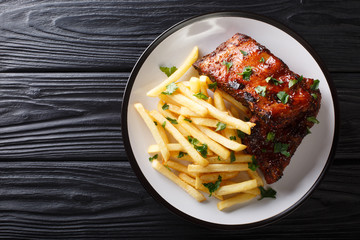Sticky short ribs with french fries close-up on a plate. Horizontal top view