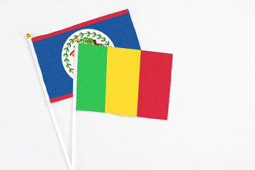 Mali and Belize stick flags on white background. High quality fabric, miniature national flag. Peaceful global concept.White floor for copy space.