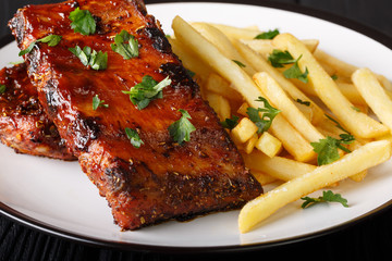 Serving barbecue short ribs with french fries close-up on a plate. horizontal