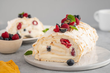 Meringue roll cake with cream and raspberries. Roulade, summer dessert, closeup.