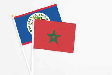 Morocco and Belize stick flags on white background. High quality fabric, miniature national flag. Peaceful global concept.White floor for copy space.
