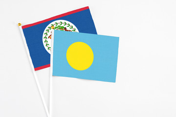 Palau and Belize stick flags on white background. High quality fabric, miniature national flag. Peaceful global concept.White floor for copy space.