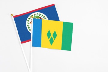 Saint Vincent And The Grenadines and Belize stick flags on white background. High quality fabric, miniature national flag. Peaceful global concept.White floor for copy space.