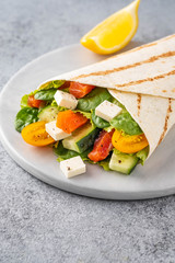 Wrap sandwich, roll with fish salmon, vegetables and cheese. Grey background. Close up.