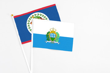 San Marino and Belize stick flags on white background. High quality fabric, miniature national flag. Peaceful global concept.White floor for copy space.