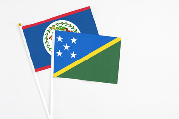 Solomon Islands and Belize stick flags on white background. High quality fabric, miniature national flag. Peaceful global concept.White floor for copy space.