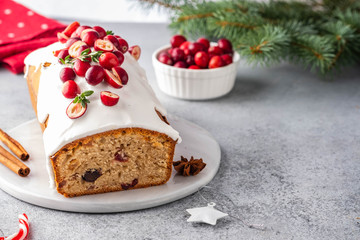 Christmas cake with cranberries and Christmas decorations on a gray background.