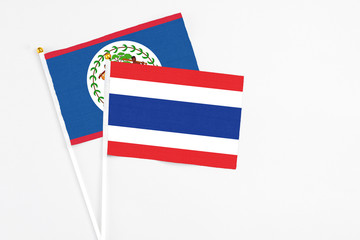 Thailand and Belize stick flags on white background. High quality fabric, miniature national flag. Peaceful global concept.White floor for copy space.