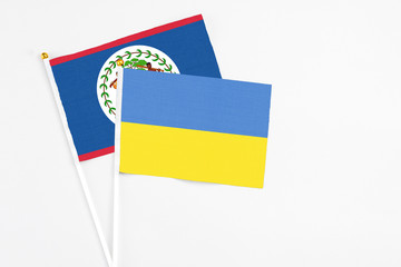 Ukraine and Belize stick flags on white background. High quality fabric, miniature national flag. Peaceful global concept.White floor for copy space.