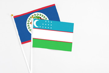 Uzbekistan and Belize stick flags on white background. High quality fabric, miniature national flag. Peaceful global concept.White floor for copy space.