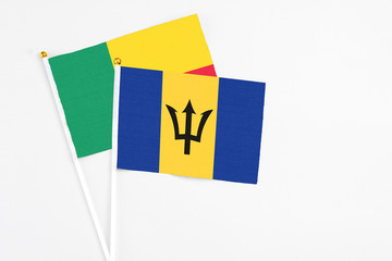 Barbados and Benin stick flags on white background. High quality fabric, miniature national flag. Peaceful global concept.White floor for copy space.