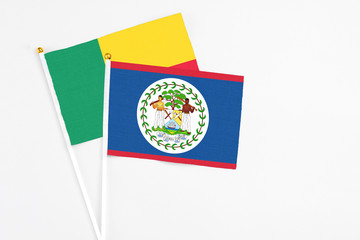 Belize and Benin stick flags on white background. High quality fabric, miniature national flag. Peaceful global concept.White floor for copy space.