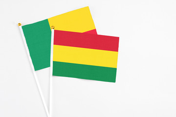 Bolivia and Benin stick flags on white background. High quality fabric, miniature national flag. Peaceful global concept.White floor for copy space.