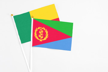 Eritrea and Benin stick flags on white background. High quality fabric, miniature national flag. Peaceful global concept.White floor for copy space.