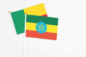 Ethiopia and Benin stick flags on white background. High quality fabric, miniature national flag. Peaceful global concept.White floor for copy space.