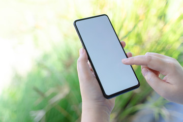 Woman using Smartphone background with green grass. Blank screen mobile phone for graphic display montage.