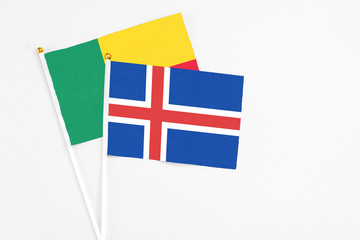 Obraz premium Iceland and Benin stick flags on white background. High quality fabric, miniature national flag. Peaceful global concept.White floor for copy space.