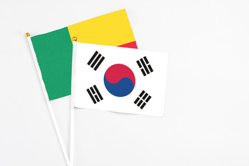 South Korea and Benin stick flags on white background. High quality fabric, miniature national flag. Peaceful global concept.White floor for copy space.