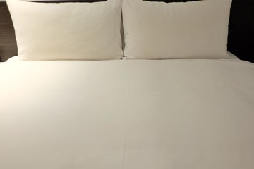 Close up a white bed room with a clean bedsheet and pillows in a private room