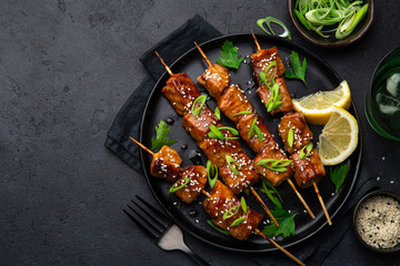 spicy teriyaki salmon skewers on black plate