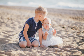 Little brother and sister posing near sea at beach