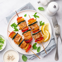 Grilled salmon and vegetables skewers on white plate