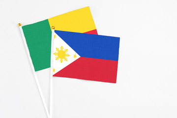 Philippines and Benin stick flags on white background. High quality fabric, miniature national flag. Peaceful global concept.White floor for copy space.