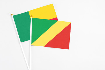 Republic Of The Congo and Benin stick flags on white background. High quality fabric, miniature national flag. Peaceful global concept.White floor for copy space.