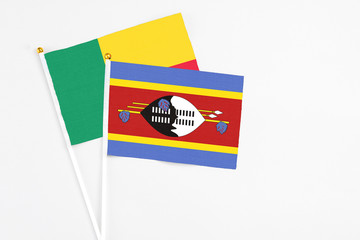 Swaziland and Benin stick flags on white background. High quality fabric, miniature national flag. Peaceful global concept.White floor for copy space.