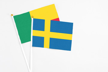 Sweden and Benin stick flags on white background. High quality fabric, miniature national flag. Peaceful global concept.White floor for copy space.