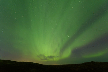 Aurora borealis over the hills. At night in the sky in the north.