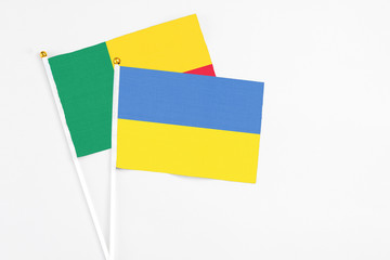 Ukraine and Benin stick flags on white background. High quality fabric, miniature national flag. Peaceful global concept.White floor for copy space.