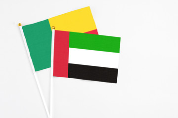 United Arab Emirates and Benin stick flags on white background. High quality fabric, miniature national flag. Peaceful global concept.White floor for copy space.
