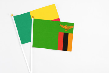 Zambia and Benin stick flags on white background. High quality fabric, miniature national flag. Peaceful global concept.White floor for copy space.