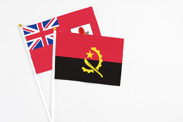 Angola and Bermuda stick flags on white background. High quality fabric, miniature national flag. Peaceful global concept.White floor for copy space.