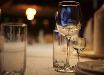 Empty glass glasses and glasses standing on a served table photographed with shallow depth of field against a background of blue bokeh circles