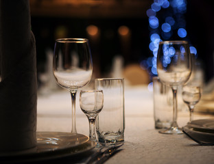 Empty glass glasses and glasses standing on a served table photographed with shallow depth of field against a background of blue bokeh circles