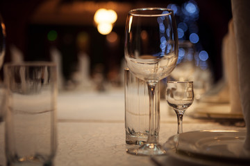 Empty glass glasses and glasses standing on a served table photographed with shallow depth of field against a background of blue bokeh circles