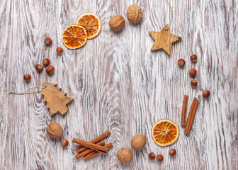 Fototapeta na wymiar Сhristmas frame made of nuts, dried oranges, cinnamon sticks. Wooden background. Flt lay, top view